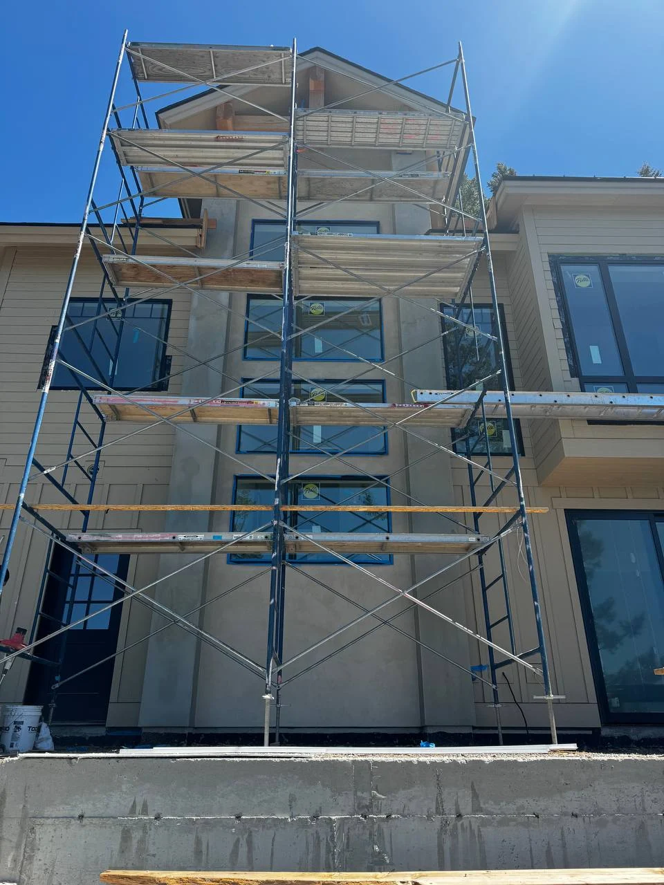 Multi-story home exterior under construction showing extensive scaffolding for a custom EIFS and stucco application by DL Construction