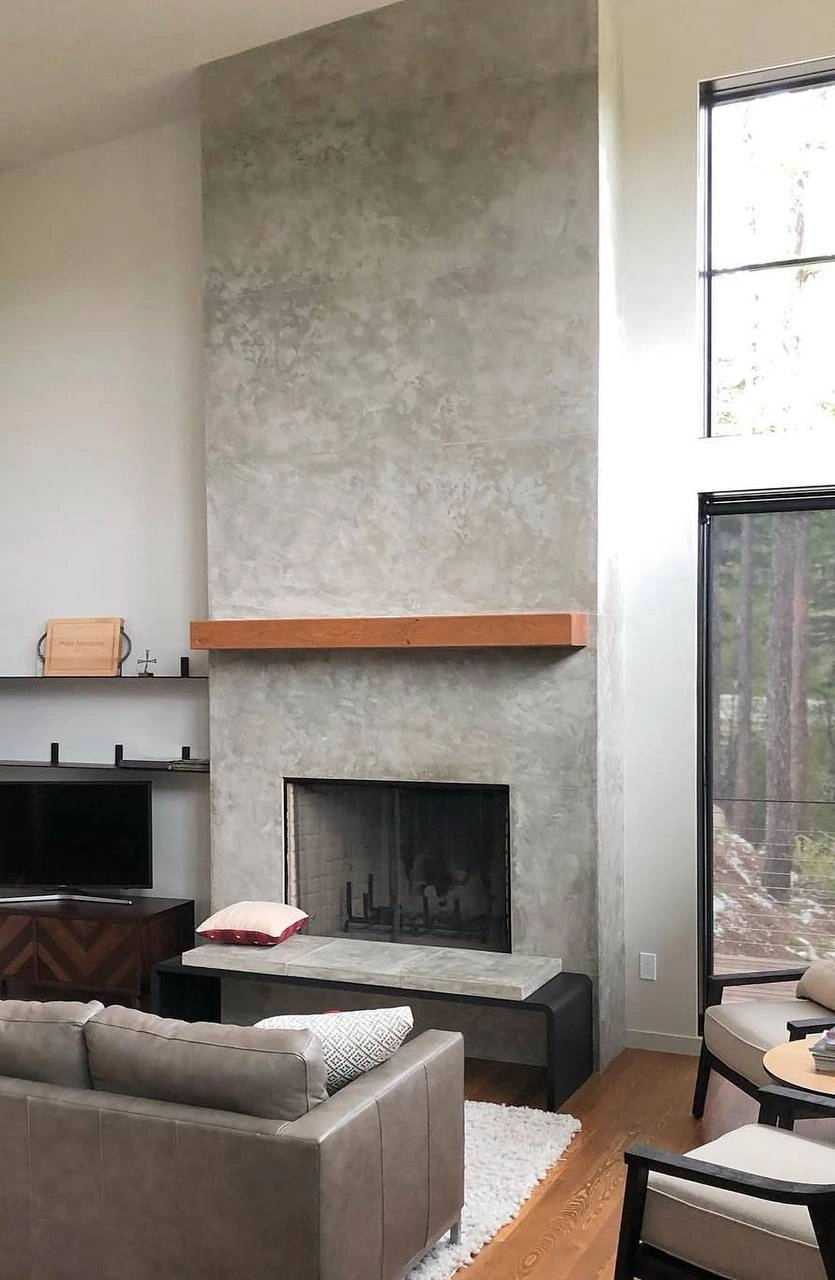 Floor-to-ceiling modern fireplace featuring a custom grey concrete-look stucco texture finish by DL Construction