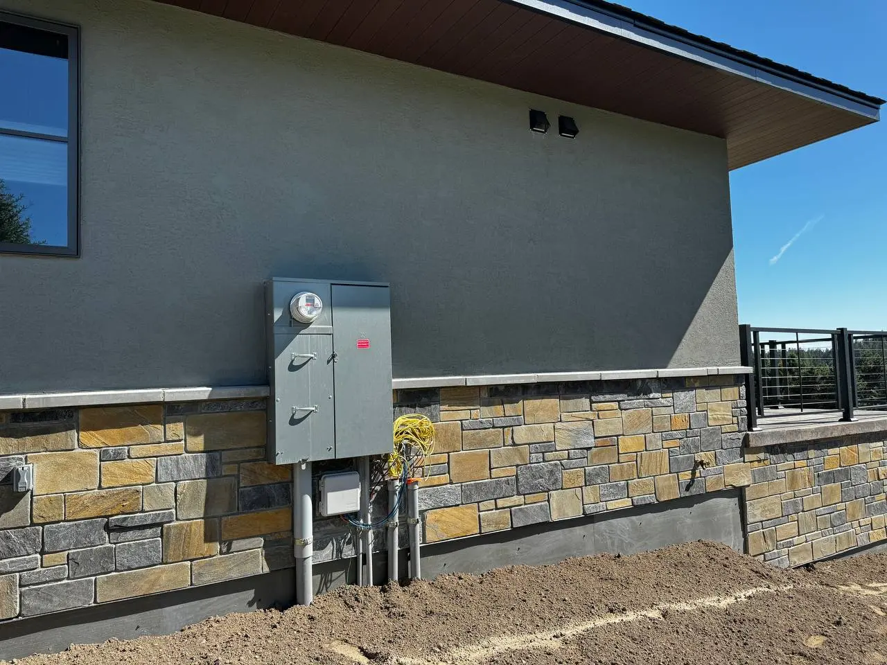Grey EIFS stucco texture integrated with a natural stone veneer base on an active residential construction site by DL Construction
