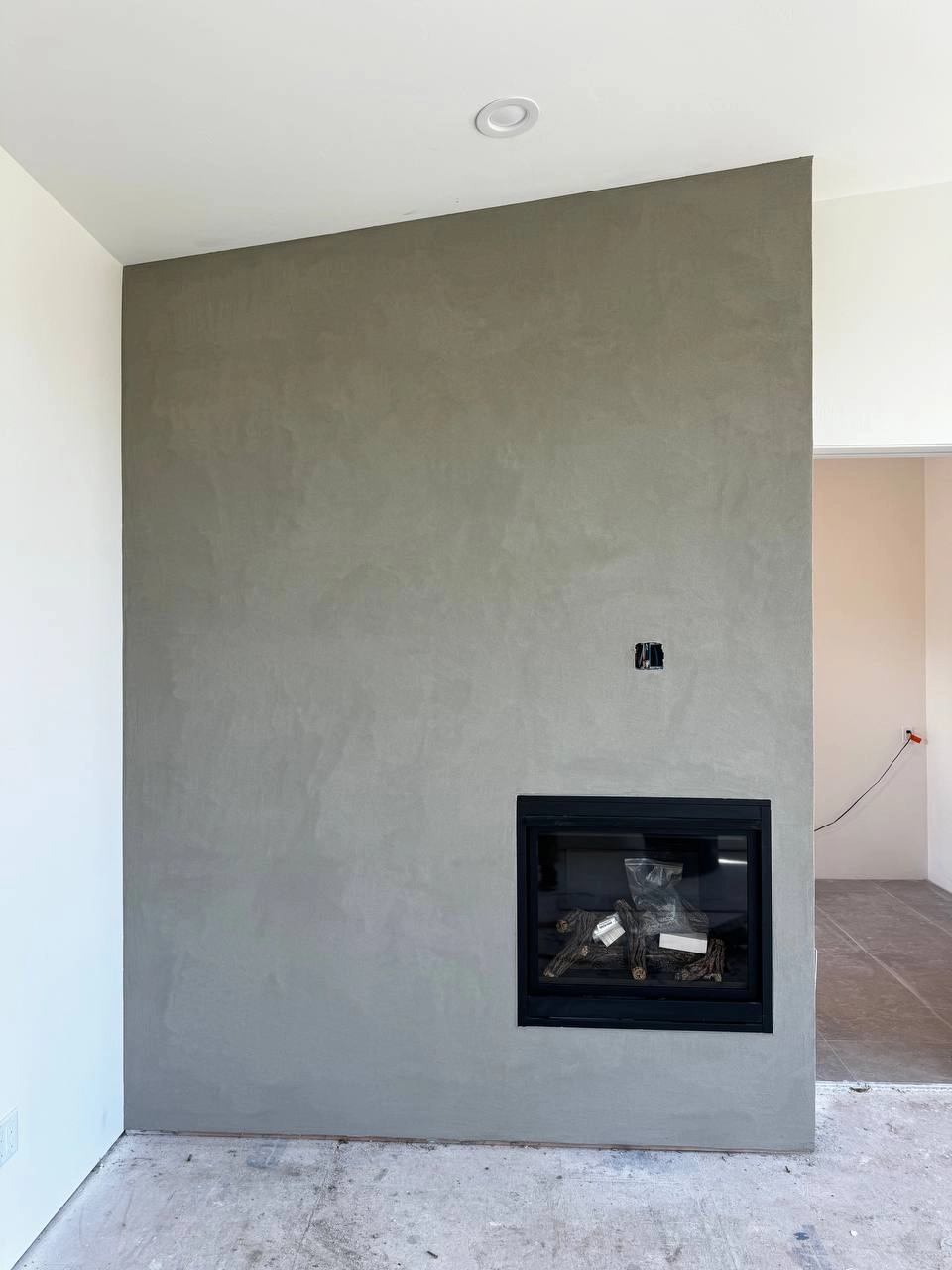 Modern indoor gas fireplace surround finished with custom smooth grey interior plaster in a Kalispell home remodeling project
