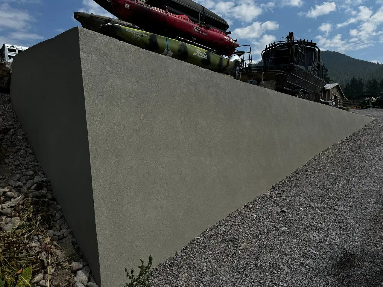 Flawless, modern stucco finish applied over a concrete retaining wall transforming the landscape next to a driveway in Kalispell, Montana